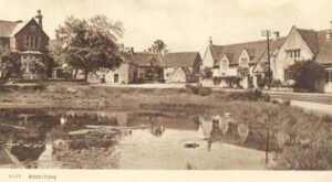 black and white postcard of Biddestone with a duck pond and houses