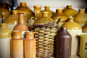 A group of light brown ceramic bottles of various sizes, with black stamps of Chippenham businesses