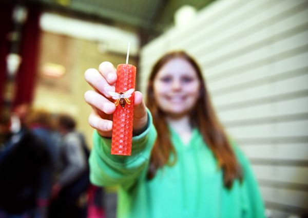candle A girl in a green jumper holding a red candle with a wasp on it