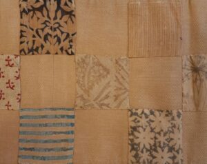 5 squares of printed textiles on a brown fabric background