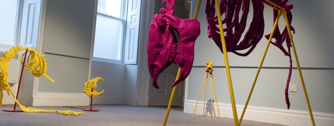harm banner image Photograph of felt fabric skeletons created by Ellie Thompson
