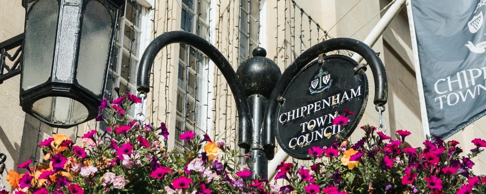 Town Hall Hanging Baskets Header Image Photograph of chippenham town council sign with pink flowers underneath it