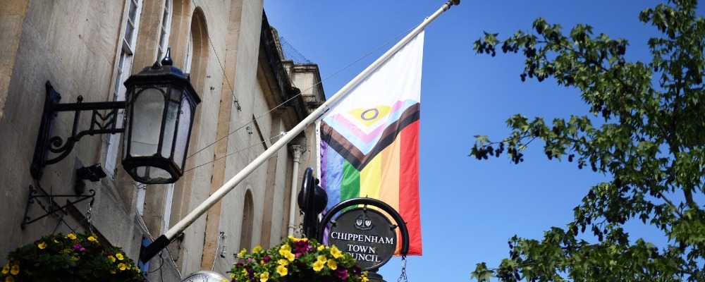 Pride Progress Flag Header Image (8) Photograph of the pride flag hung up in the chippenham high street