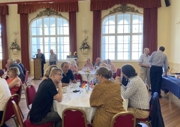 Twinning Association Visit July 2024 people sat around tables in various groups in the town hall