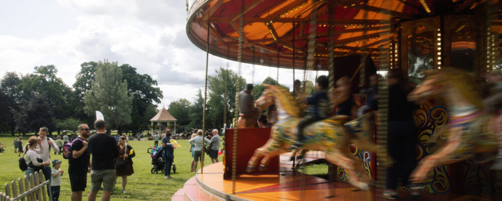john coles park Photograph of a carousel in John coles park with people all around the park