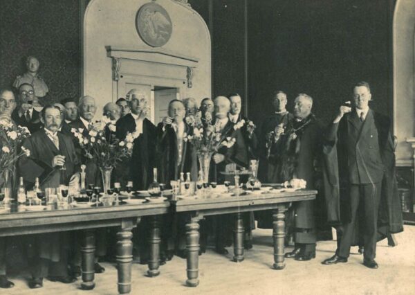 Into the 20th Century 2 Black and white vintage photo of a group of men in suits raising their glasses