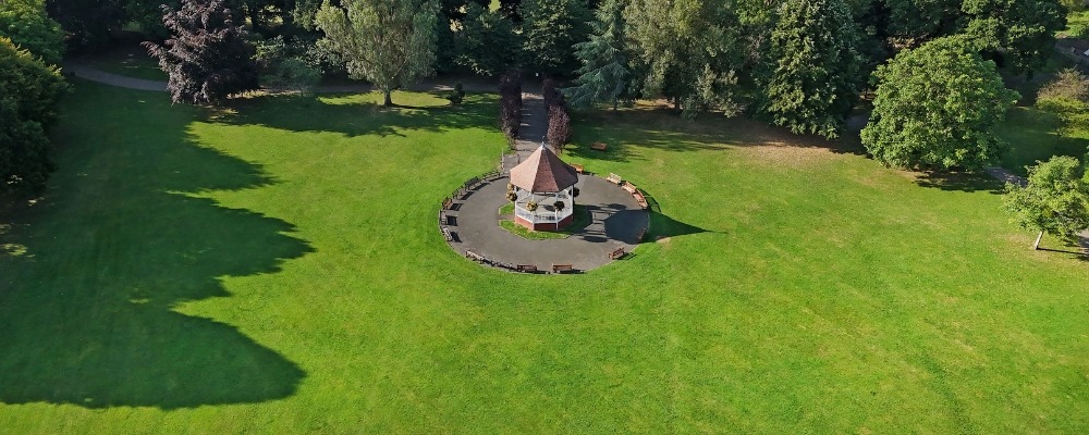 Photograph from above of the band stand in John Coles park with green grass and trees