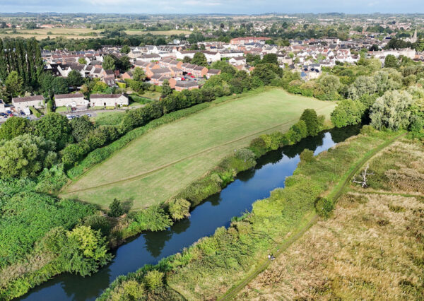 default Photgraph of a small green field with trees and a river