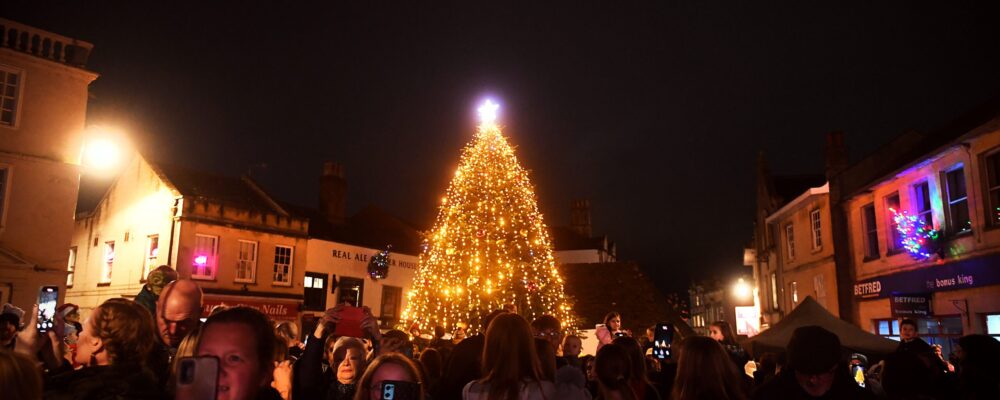 Christmas Tree 2024 An outdoor lit up Christmas tree, surrounded by a crowd of people.
