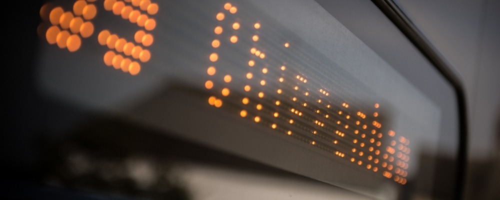 Low Carbon Transport A close-up of an illuminated sign displaying orange dot-matrix letters on a bus header that reads 55 Chippenham