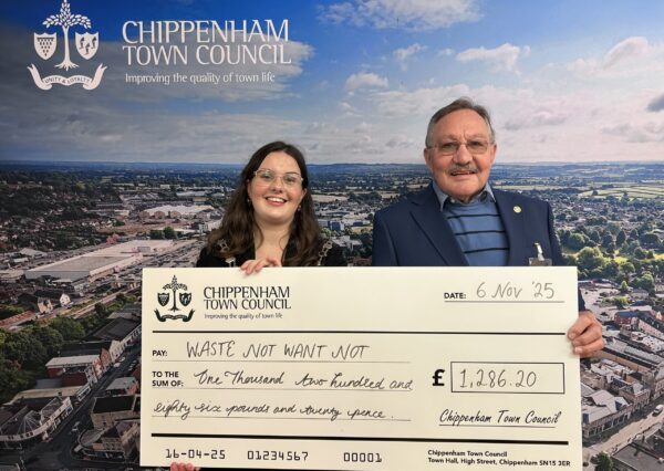 Council Grants Scheme Two people stand smiling in front of a Chippenham Town Council backdrop, holding a large check awarding £1,286.20 to Waste Not Want Not.