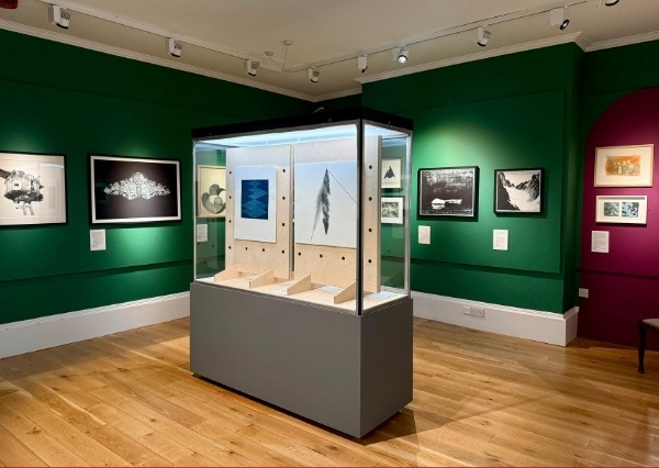 Chippenham Museum An image of a gallery with framed artwork on the walls and a large case in the centre of the room with more artworks inside.