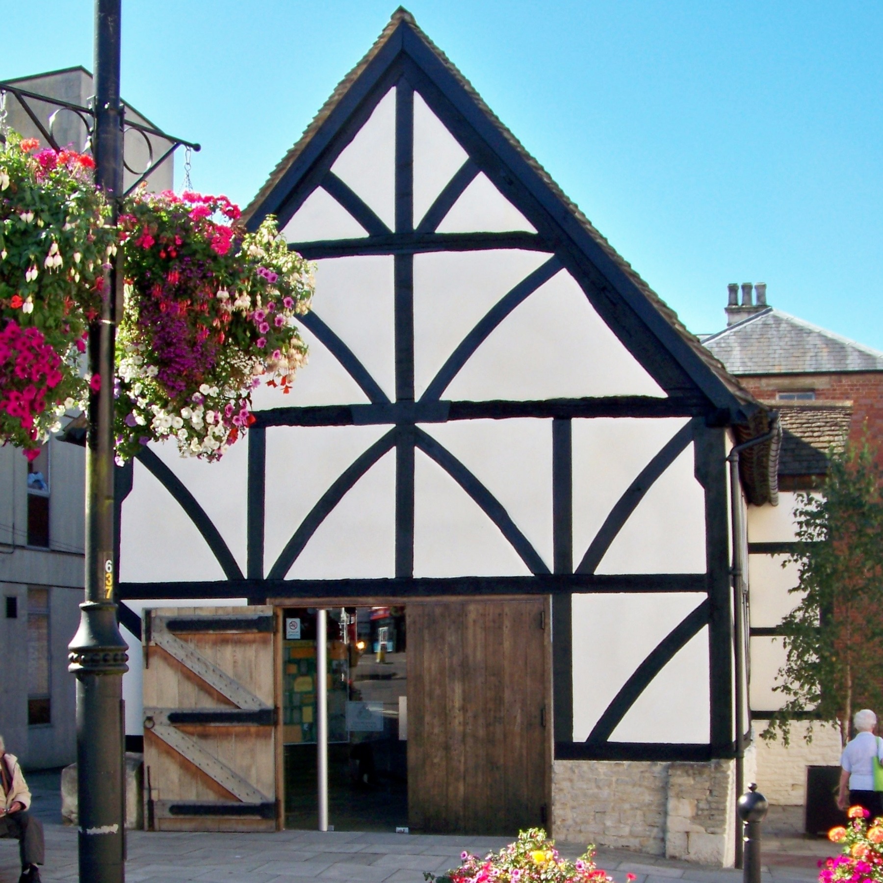Black timber and white plaster building with large wooden doors open to welcome public.