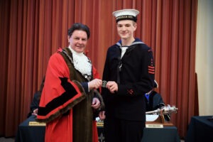 Photograph showing Mayor of Chippenham, Matthew Bragg, wearing the Mayoral Robe, presenting an award to new Mayoral Cadet Reuban. Photograph showing Mayor of Chippenham, Matthew Bragg, wearing the Mayoral Robe, presenting an award to new Mayoral Cadet Reuban.